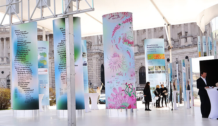 Das Foto zeigt den Pavillon von außen mit der von den Künstlerinnen Daniela Brasil und Silvana Beraldo gestalteten Stele